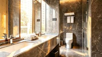 Un baño moderno con un espejo grande, dos lavamanos, un inodoro y una cabina de ducha de vidrio.