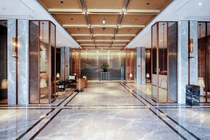 Una hall d'albergo moderna con pavimento in marmo, separé in legno e reception.