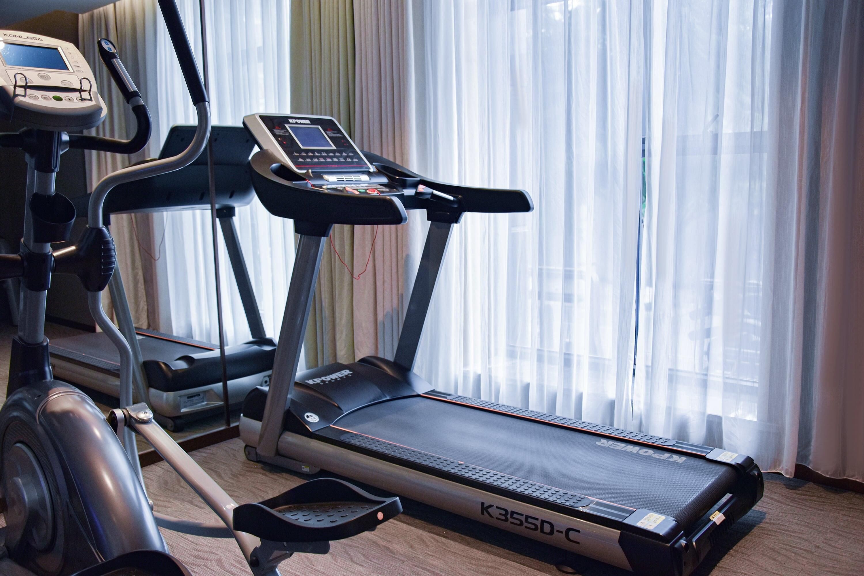 Una cinta de correr con pantalla digital y una bicicleta estática con monitor de frecuencia cardíaca.