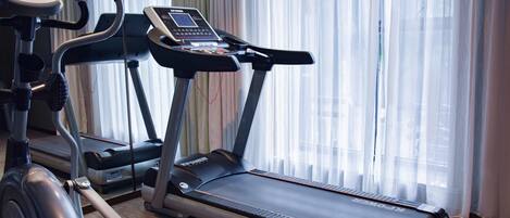 Una cinta de correr con pantalla digital y una bicicleta estática con monitor de frecuencia cardíaca.