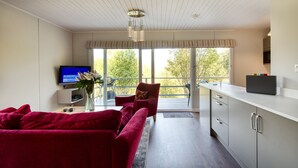 Una sala de estar moderna con un sofá rojo, un televisor y un florero con flores.