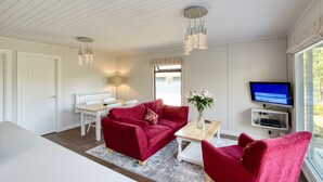 Una sala de estar moderna con un sofá rojo, una mesa de centro blanca y un televisor sobre un mueble.