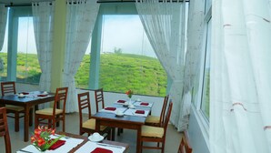A dining area with tables set for four, chairs, and a vase with flowers. - Lourdes Hotel (Nuwara Eliya)