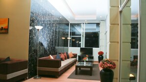 A modern living room with a sofa, coffee table, and a large window. - Lourdes Hotel (Nuwara Eliya)