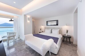 Enjoy a serene sea view from the large window in this stylish room featuring a comfortable bed and a cozy seating area.