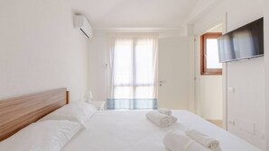 Ein Hotelzimmer mit einem Bett, einem an der Wand befestigten Fernseher und einem Fenster mit Vorhängen.
