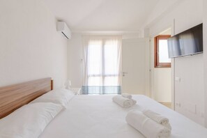 Une chambre d’hôtel avec un lit, un téléviseur fixé au mur et une fenêtre avec des rideaux.