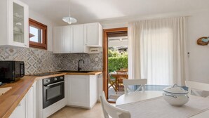 Eine kompakte Küche mit weißen Schränken, einer Mikrowelle, einem Backofen und einem Essbereich mit Tisch und Stühlen.