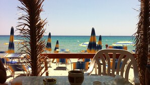 Ein Restaurant direkt am Strand mit Außenbereich, Sonnenschirmen und Meerblick.