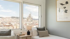 A bedroom with two beds, a nightstand, a lamp, and a framed artwork. - Amazing skyline with amazing views (Barcelona)