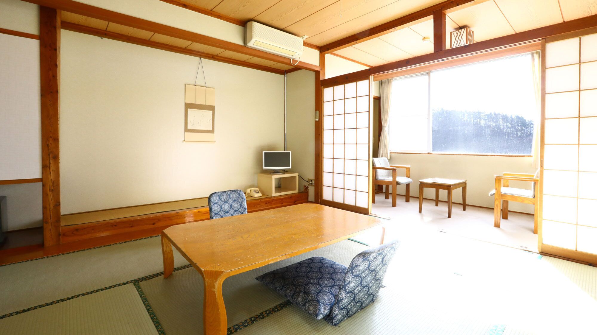 A traditional Japanese room with tatami flooring, a wooden table, and sliding doors.