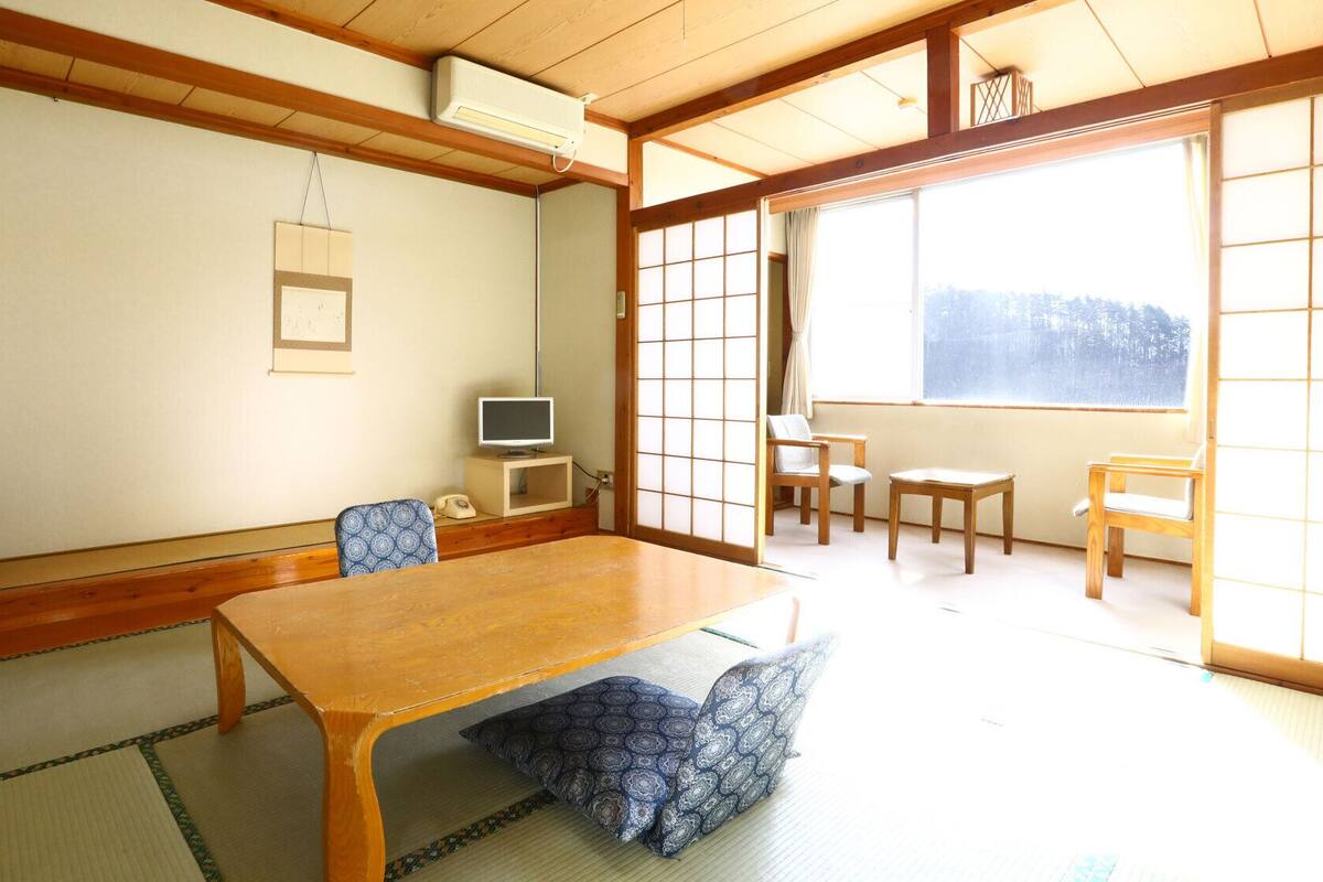 Una habitación japonesa tradicional con suelo de tatami, una mesa de madera y puertas correderas.