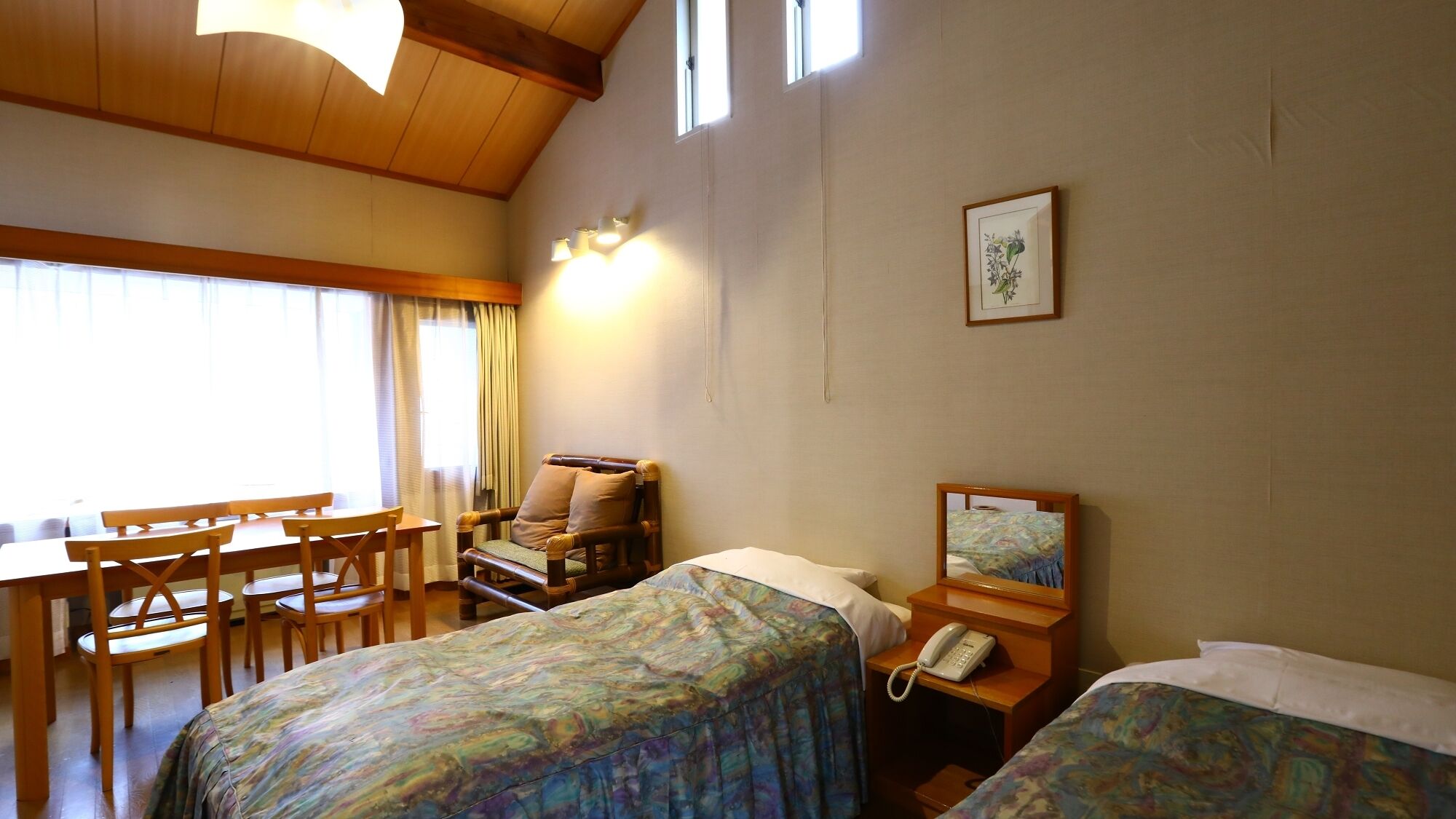 A hotel room with two beds, a desk, a chair, a telephone, and a painting on the wall.