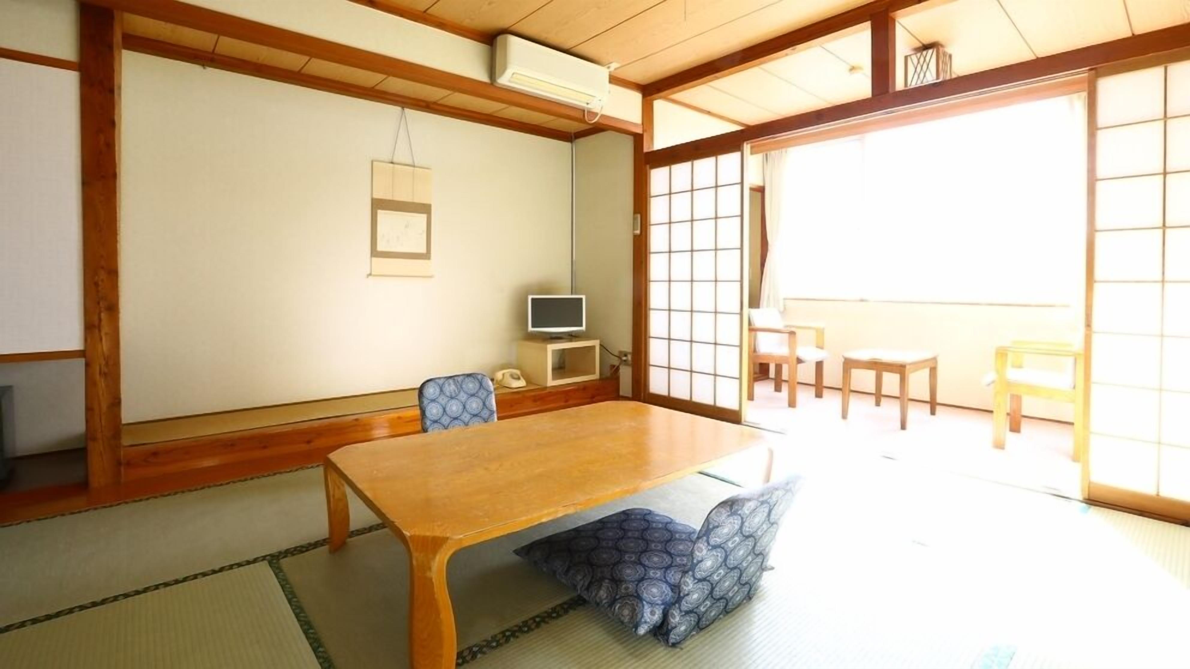 A traditional Japanese room with tatami flooring, a wooden table, and sliding doors.