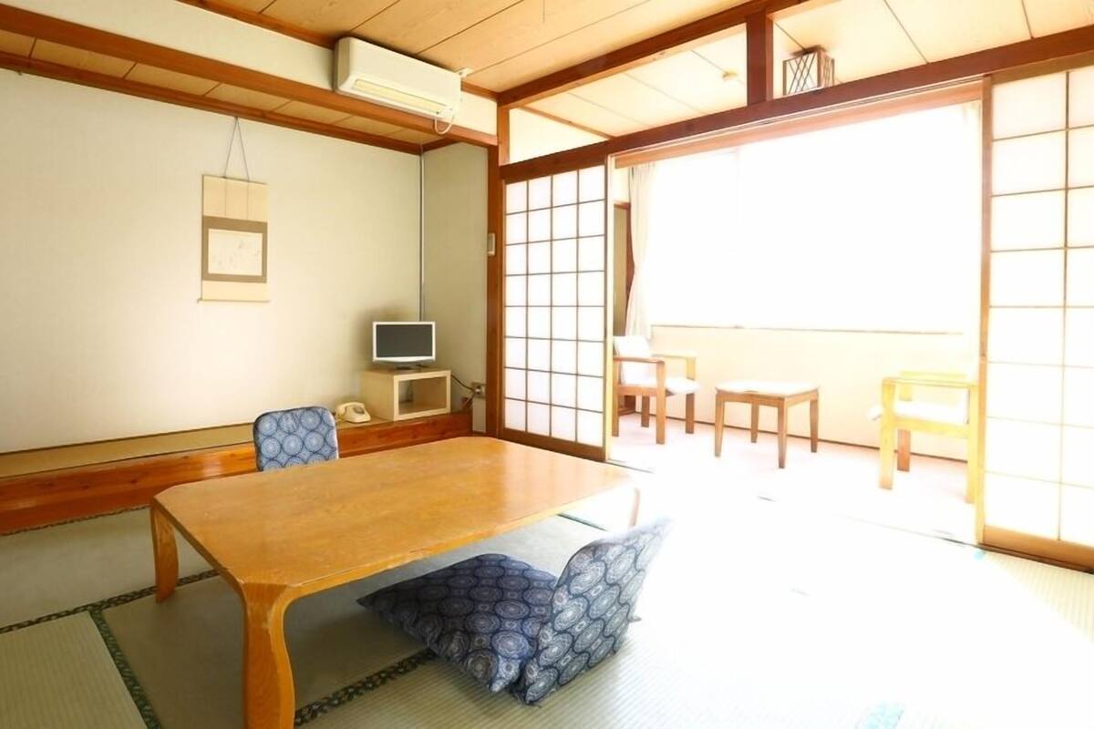 Una habitación japonesa tradicional con suelo de tatami, una mesa de madera y puertas correderas.