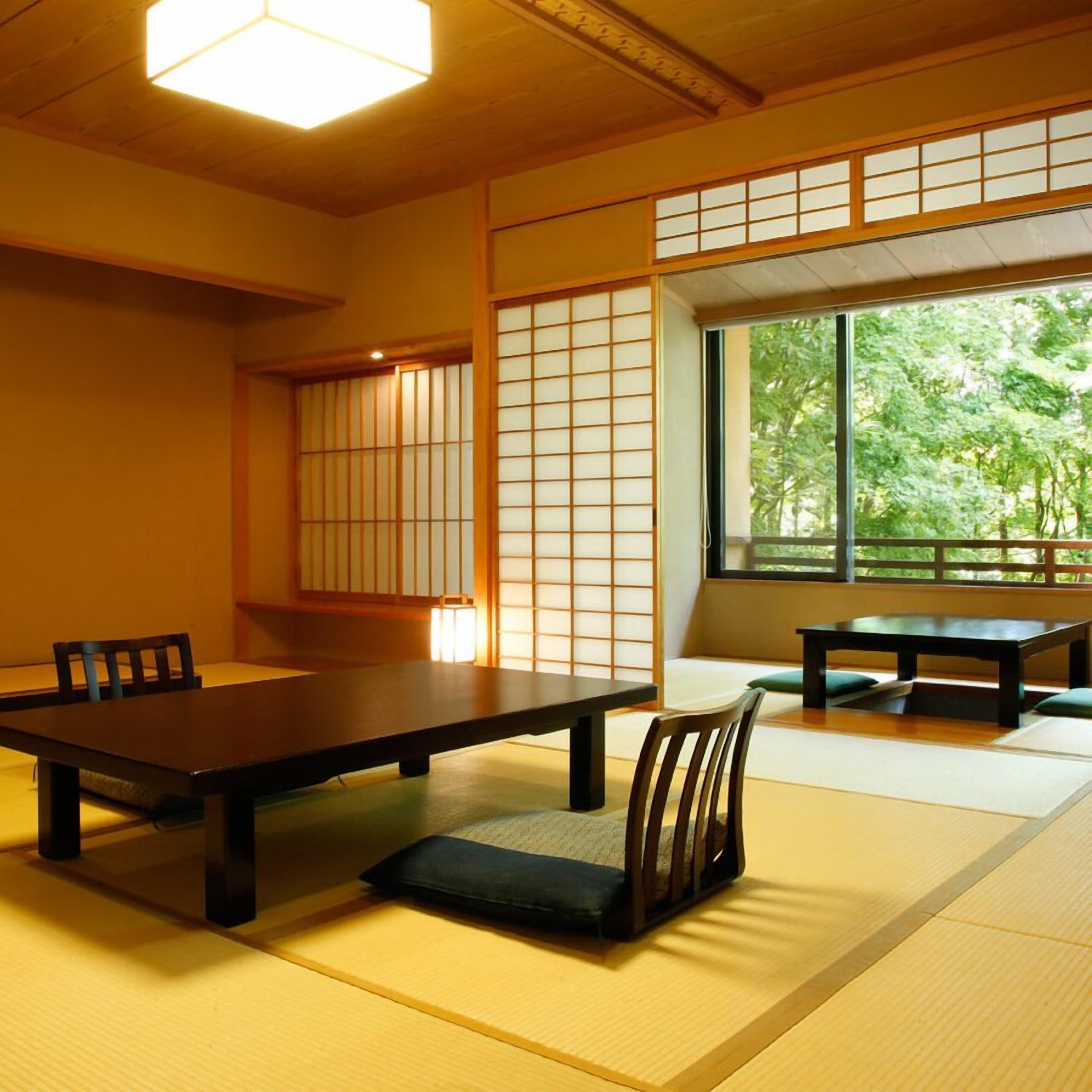 Een traditionele Japanse kamer met tatami vloeren, een lage tafel, stoelen en verschuifbare shoji deuren.
