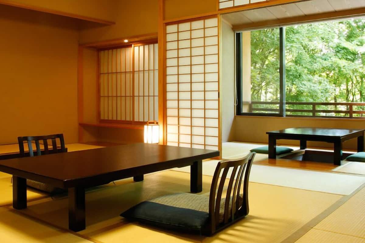 Ett traditionellt japanskt rum med tatamimattor på golvet, ett lågt bord, stolar och skjutbara shojidörrar.