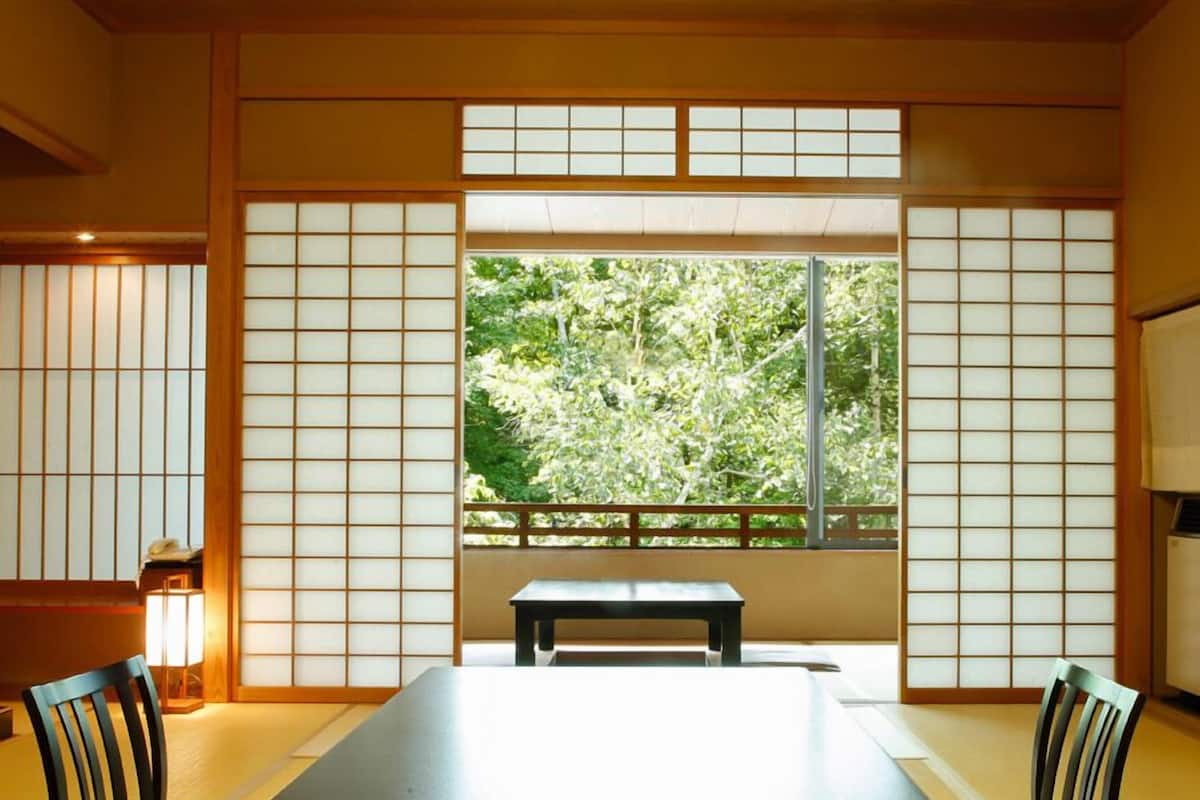 Ett traditionellt japanskt rum med tatamimattor på golvet, ett lågt bord och shojiskärmar.