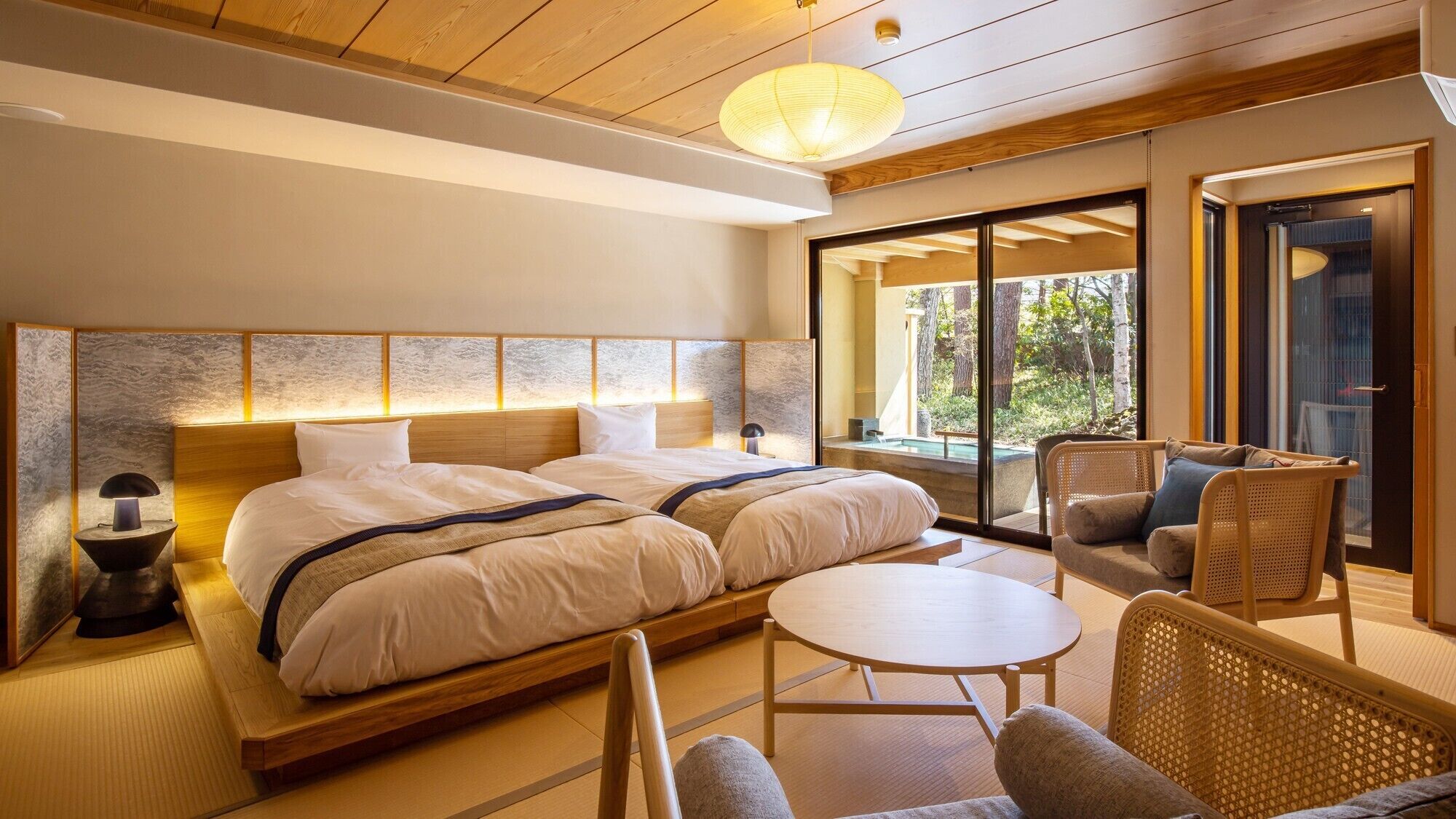A hotel room with a bed, two bedside tables, a small round table, and a chair.