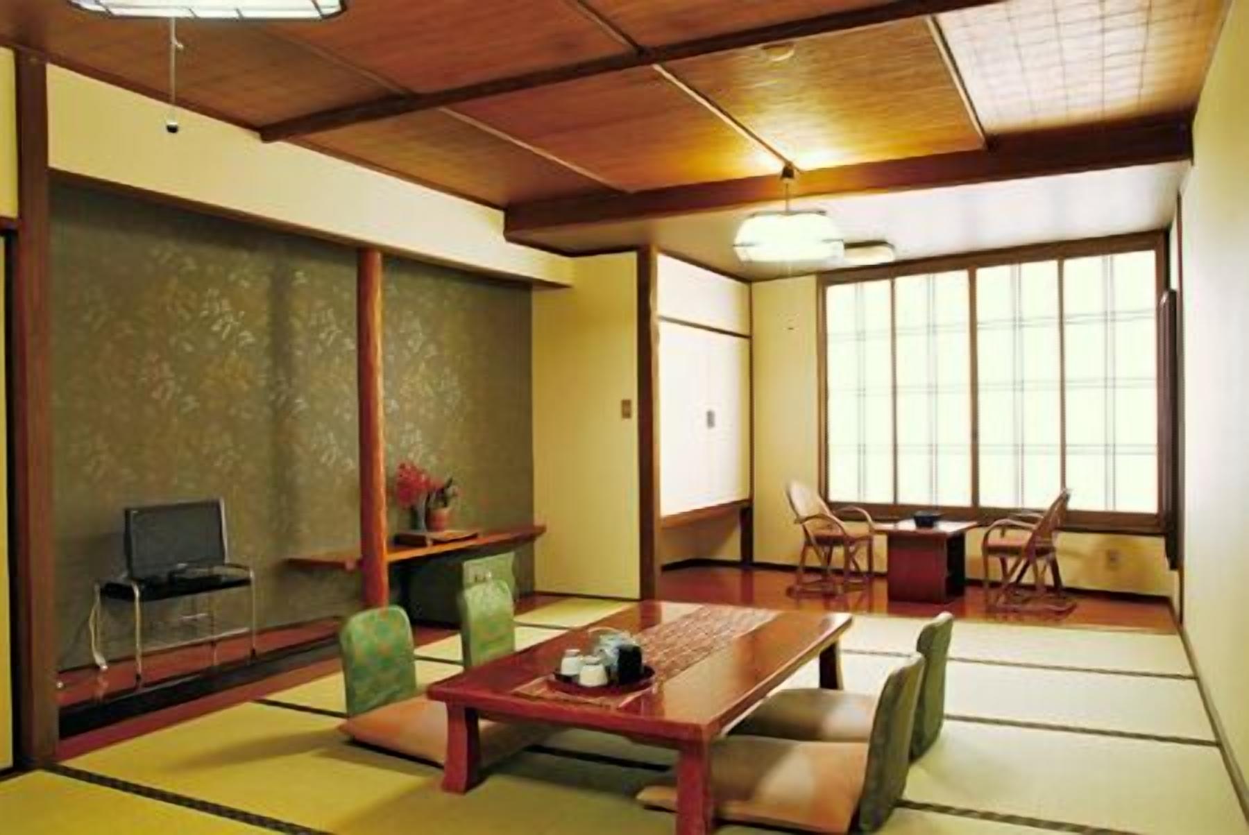 Ein traditioneller japanischer Raum mit Tatami-Bodenbelag, einem niedrigen Tisch, Stühlen und einer Schiebetür.