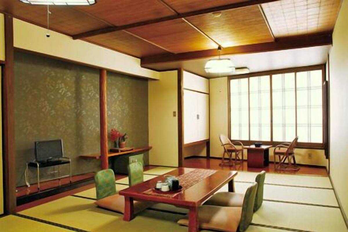 A traditional Japanese room with tatami flooring, a low table, chairs, and a sliding door.