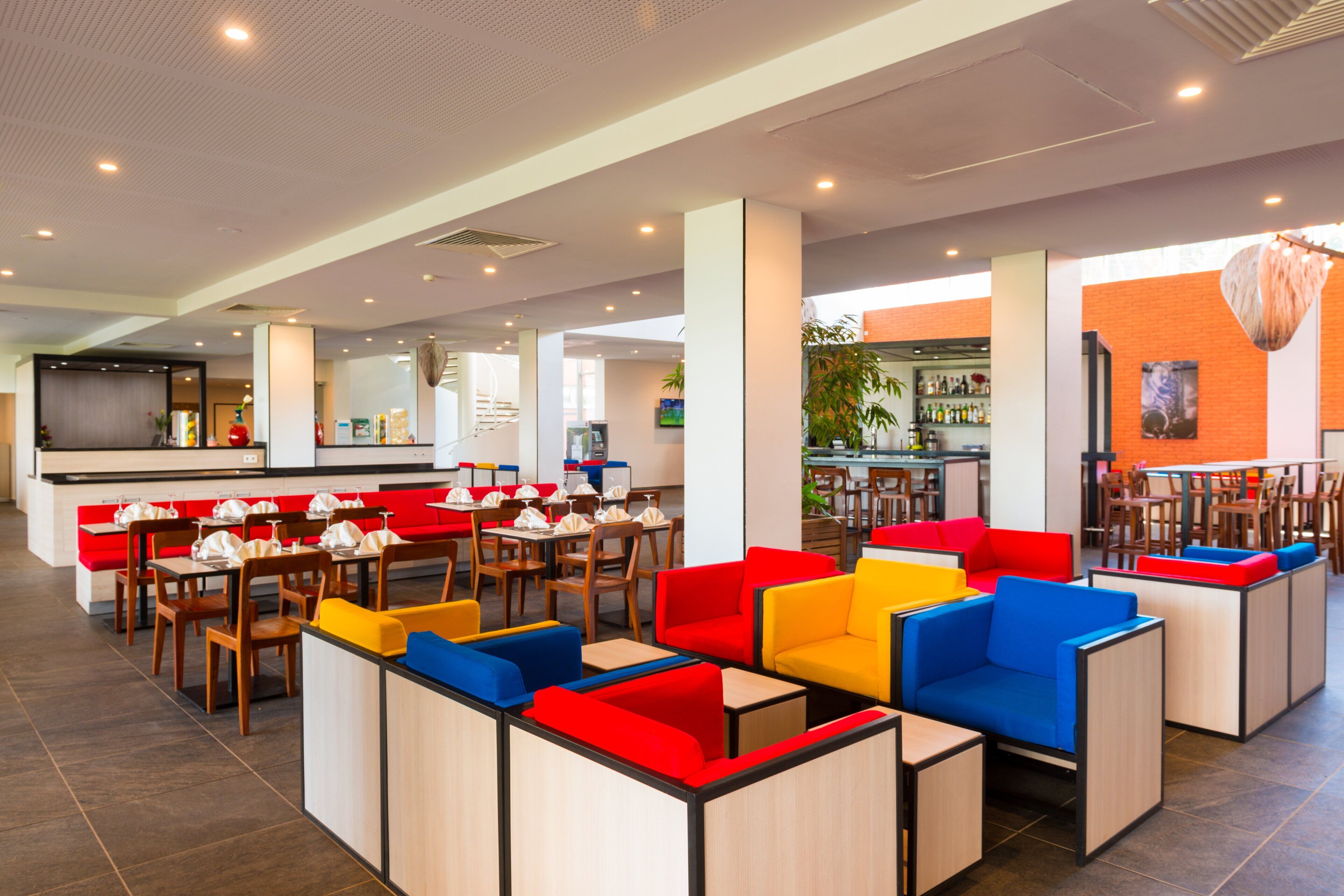 A modern restaurant with high tables and booths, a bar area, and a brick accent wall.