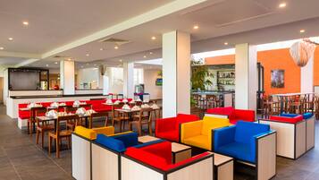 A modern restaurant with high tables and booths, a bar area, and a brick accent wall.