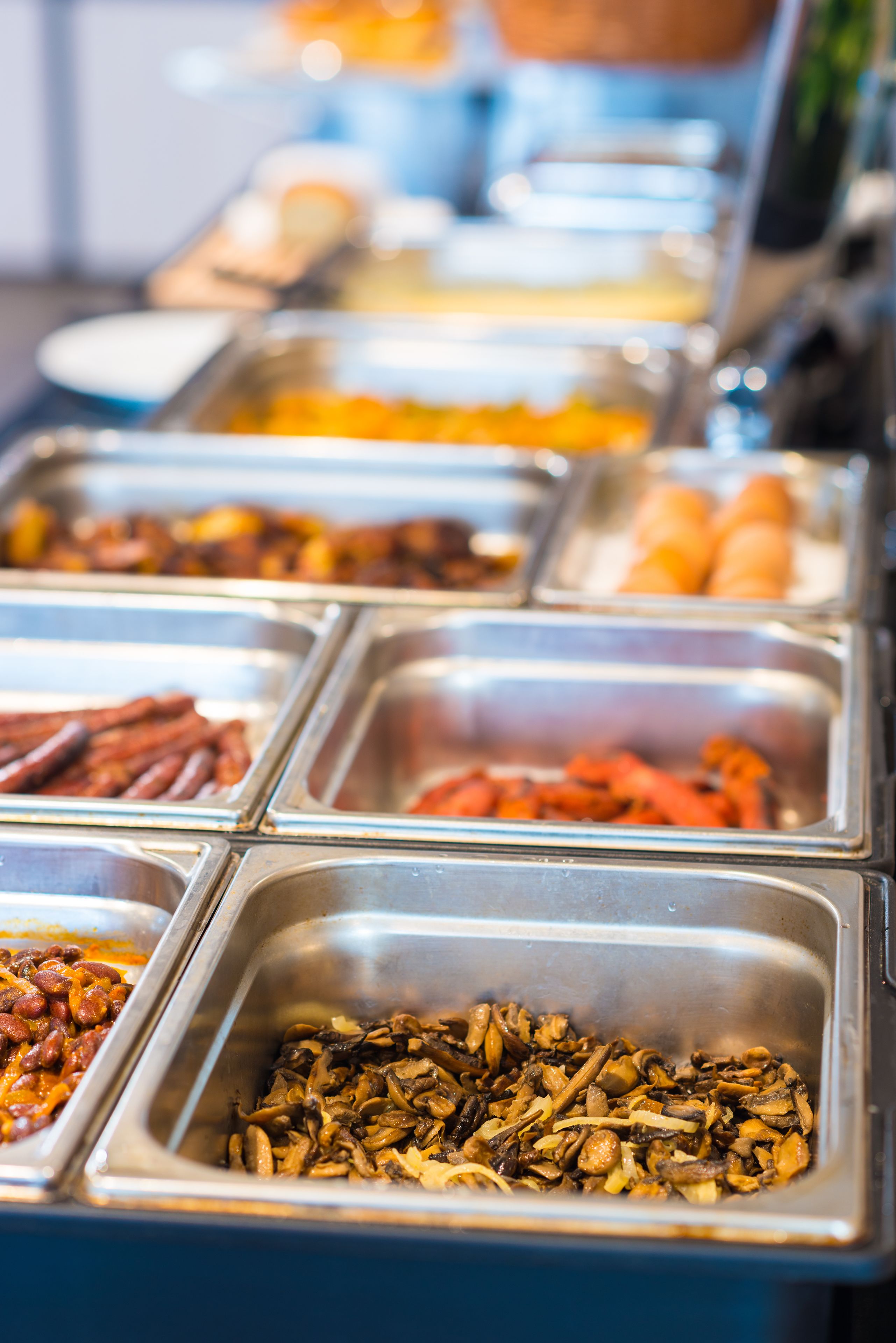 Ein Buffet mit verschiedenen Speisen, darunter Bohnen, Würstchen und Pilze.