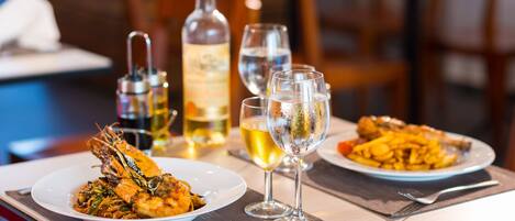Una mesa de comedor con dos platos de comida, una botella de vino y dos copas de vino.