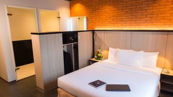 A hotel room with a bed, a desk, a microwave, and a brick wall.