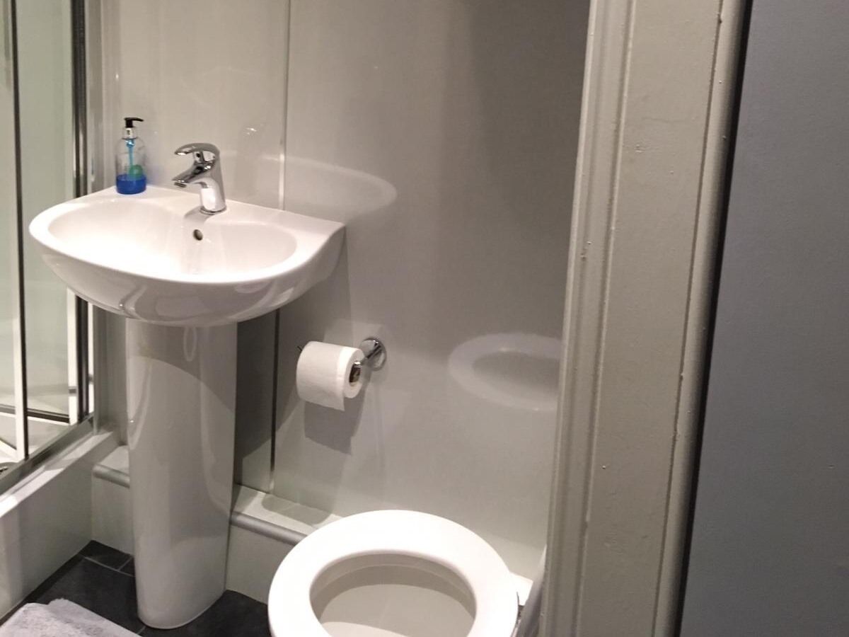 Un baño con un lavabo blanco, un inodoro y una cabina de ducha de vidrio.