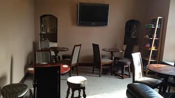 Un salon avec un téléviseur fixé au mur, une table basse, un canapé et une bibliothèque.