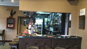 A bar area with a counter, stools, and a shelf with bottles. - Macbeth Arms (Banchory)