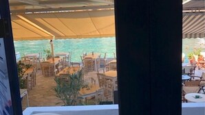 An outdoor dining area with tables and chairs, a covered seating area, and a view of the sea. - Macbeth Arms (Banchory)