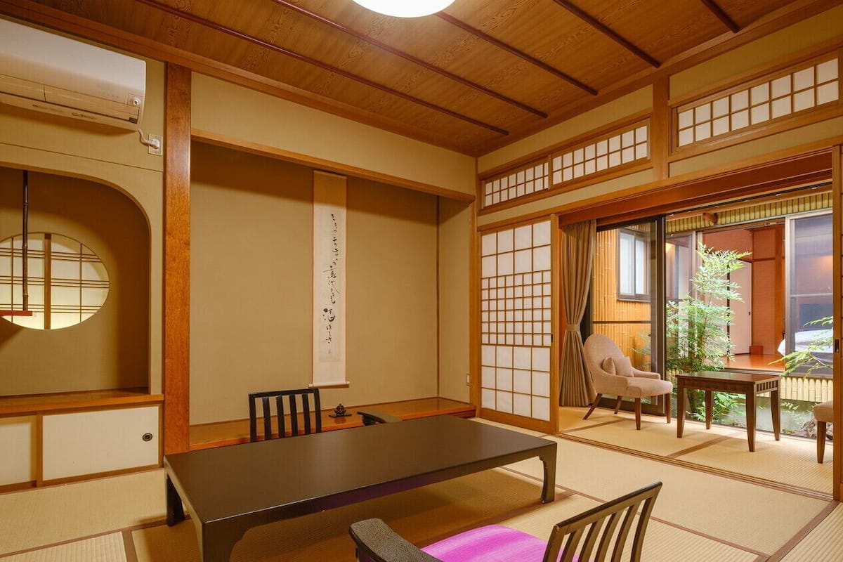 Una habitación japonesa tradicional con suelo de tatami, una mesa baja y puertas correderas.