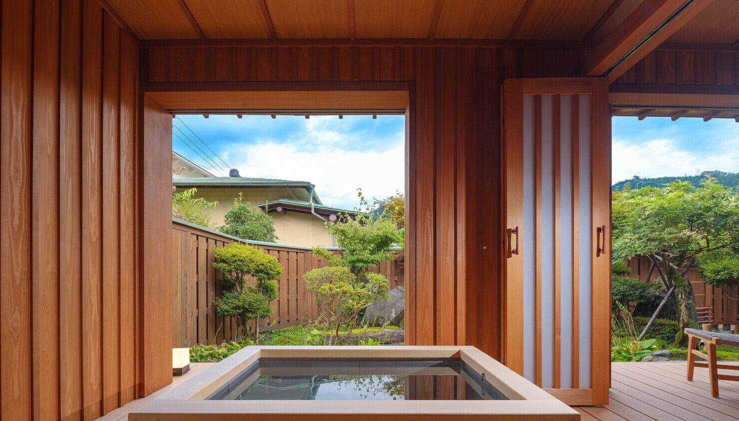 A wooden room with a view of a garden and a hot tub.