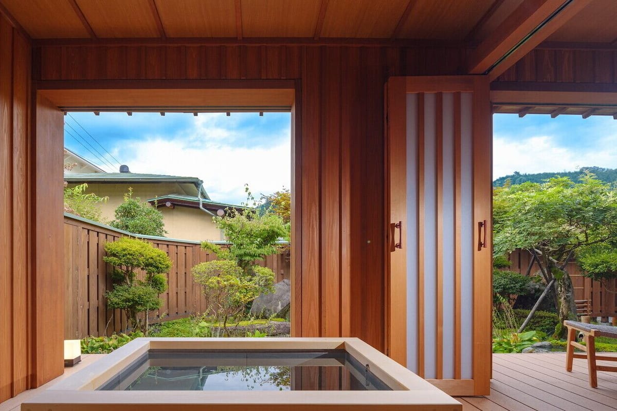 Una habitación de madera con vistas a un jardín y un jacuzzi.
