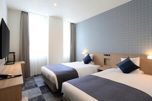 Habitación de hotel con dos camas, televisión, escritorio y ventana con cortinas.