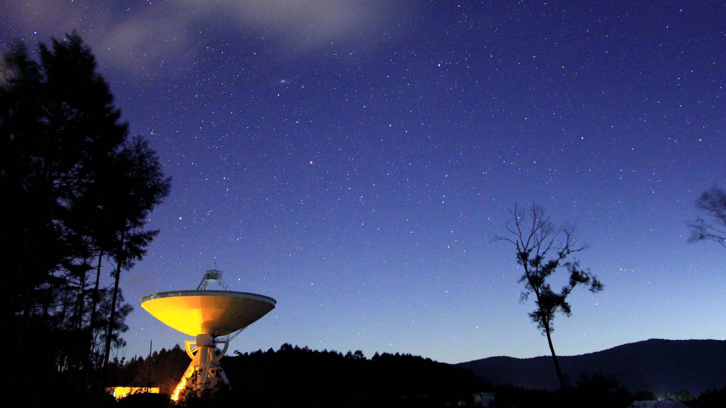 A satellite dish with a clear night sky in the background.