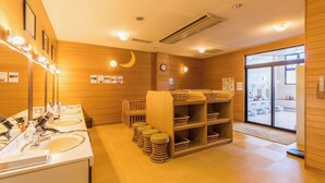 A wooden interior with a reception desk, multiple sinks, and a large mirror.