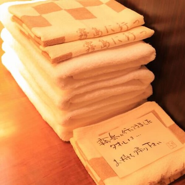 A stack of folded towels with Japanese text on them. - Tsumikusa no Yado Komatsu (Kirishima)