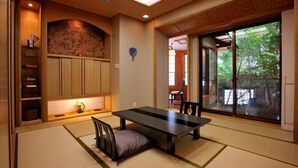 A traditional Japanese-style room with tatami flooring, a low table, and sliding doors leading to a garden. - Tsumikusa no Yado Komatsu (Kirishima)
