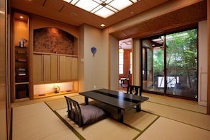 A traditional Japanese-style room with tatami flooring, a low table, and sliding doors leading to a garden. - Tsumikusa no Yado Komatsu (Kirishima)