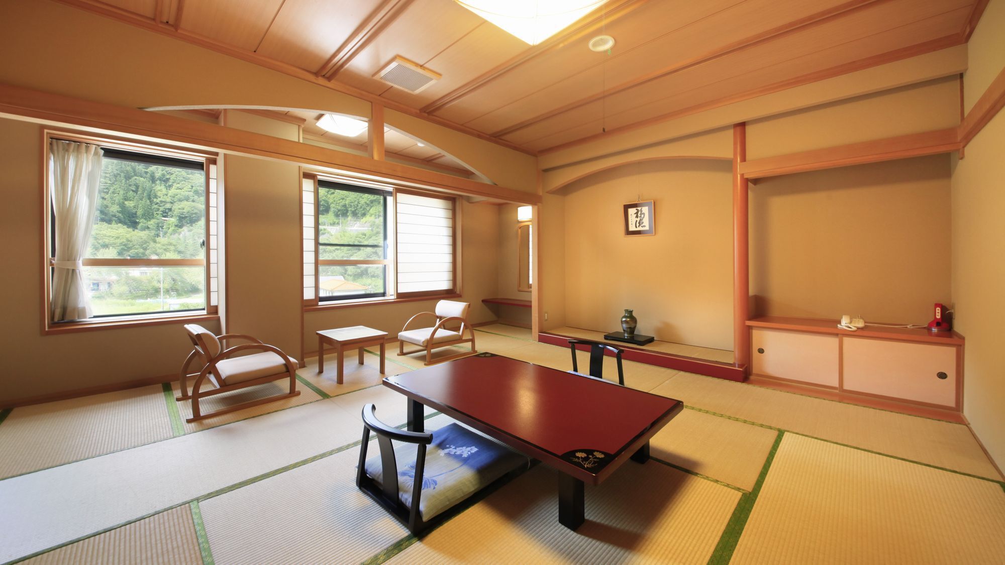A traditional Japanese room with tatami flooring, a low table, chairs, and a sliding door.