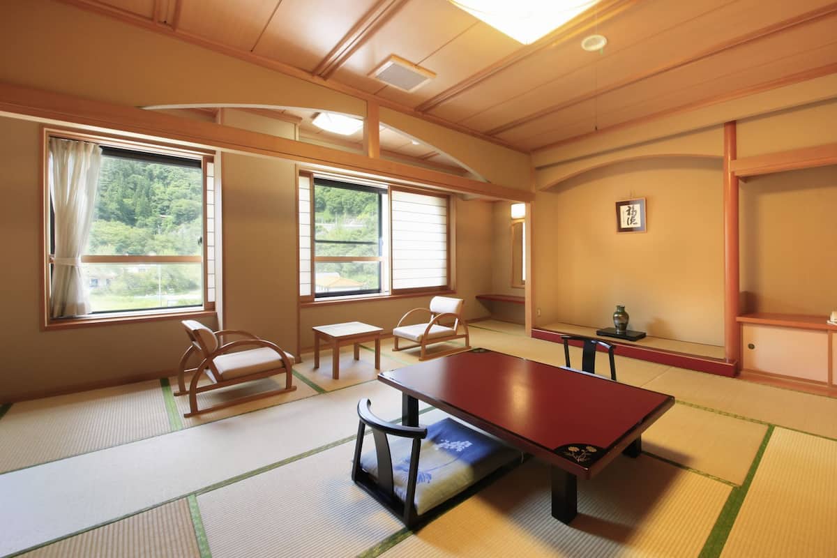 A traditional Japanese room with tatami flooring, a low table, chairs, and a sliding door.