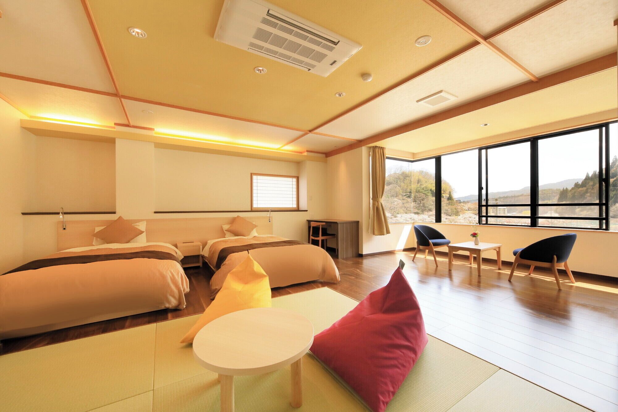 Habitación de hotel con cama, escritorio, silla, mesita y un gran ventanal con vistas.
