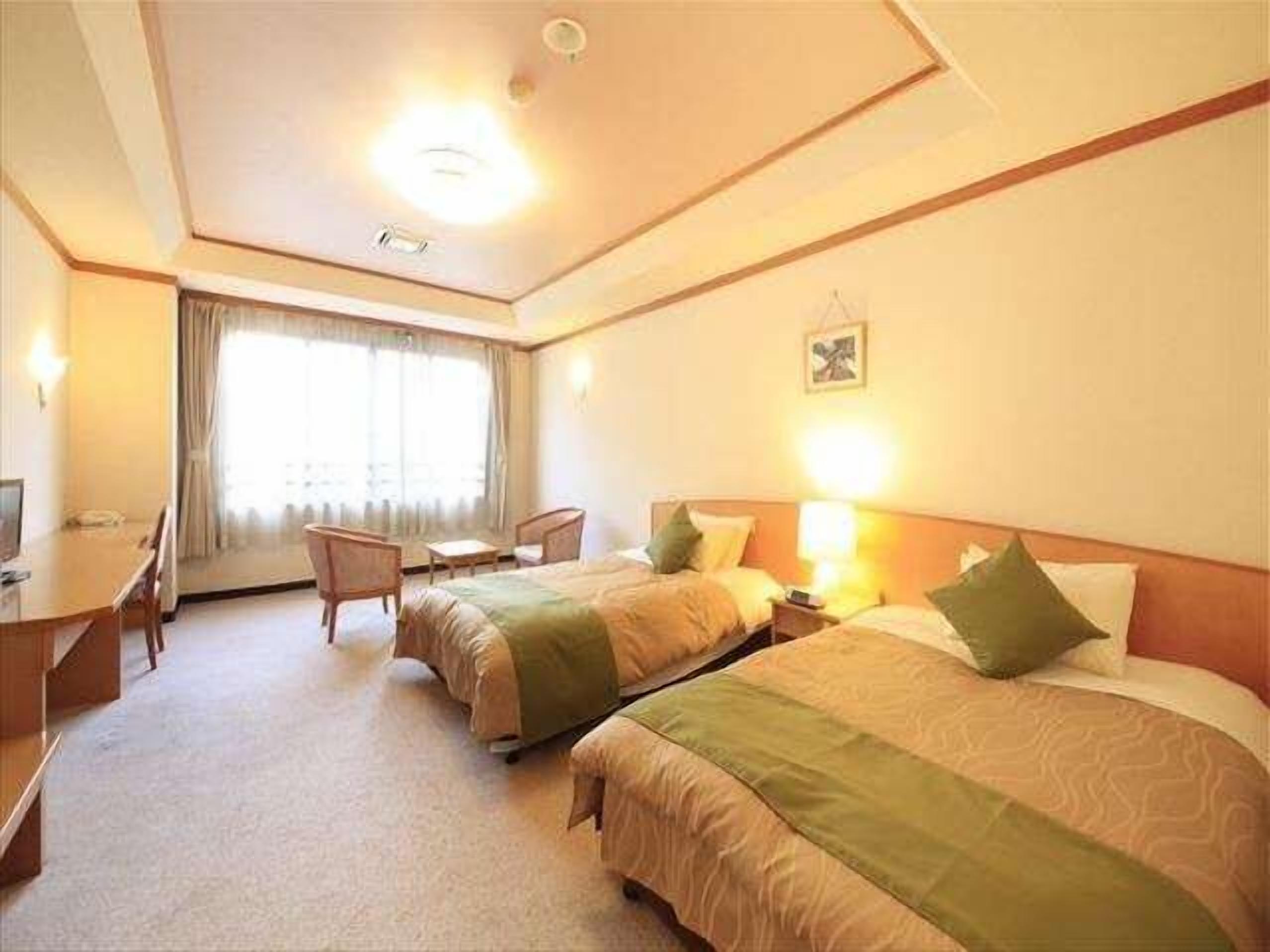 Une chambre d’hôtel avec deux lits, un bureau et une chaise.