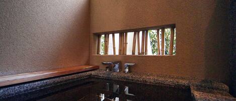 Un bagno con un piano in granito, uno specchio e una finestra con persiane verticali.