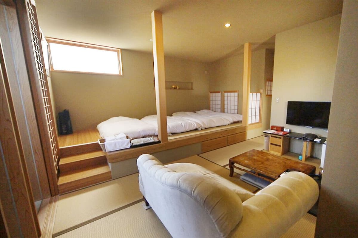 A room with a bed, a sofa, a TV, and a wooden desk.