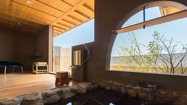 Un interior moderno con una piscina revestida de piedra, suelo de madera y un gran ventanal con vistas al exterior.